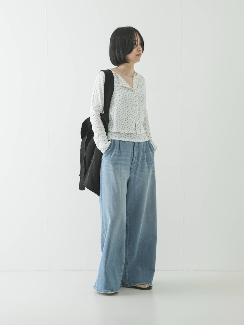 ブルー系のカーディガン/ボレロ、ブラック系のトートバッグ、ブルー系のデニムパンツを着用したレディースの春コーディネートの2枚目の写真