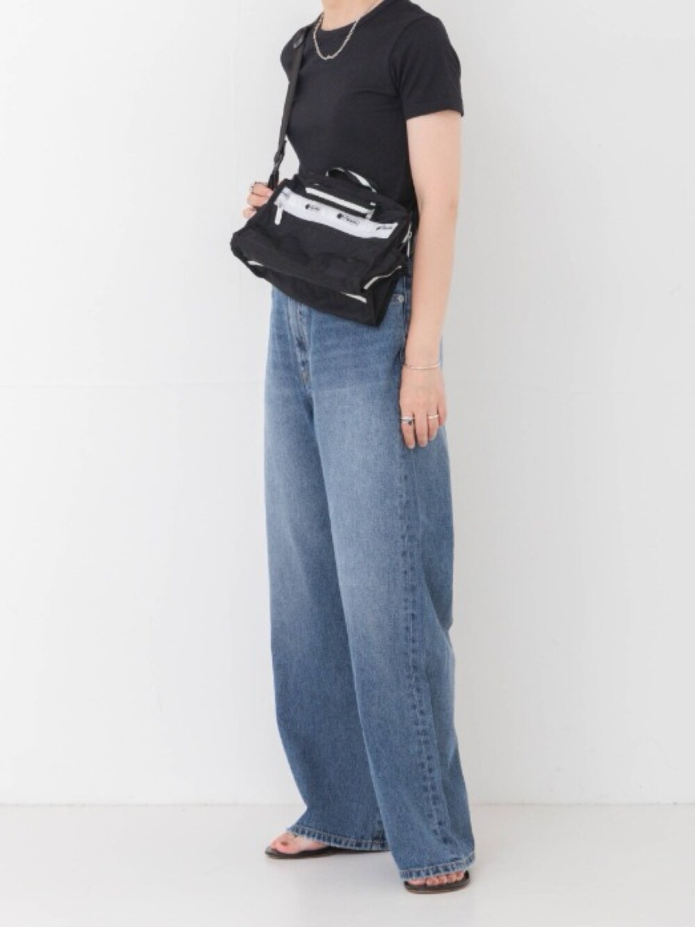 ブラック系のTシャツ/カットソー、ブラック系のショルダーバッグ、ブルー系のデニムパンツを着用したレディースの夏コーディネートの3枚目の写真