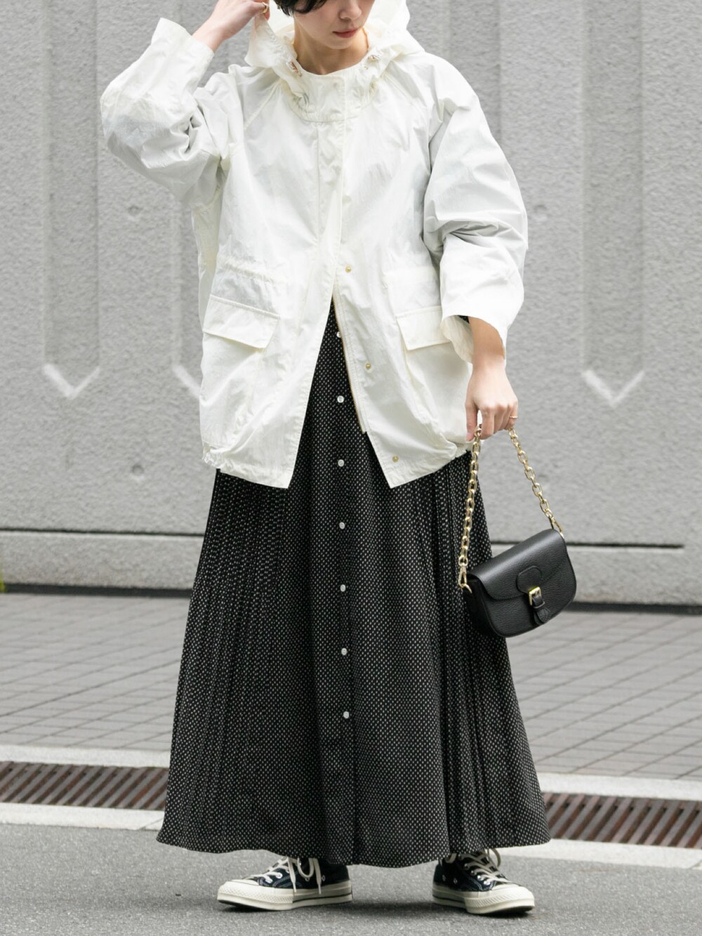 ホワイト系のマウンテンパーカー、ブラック系のショルダーバッグ、ブラック系のワンピースを着用したレディースの春コーディネートの2枚目の写真