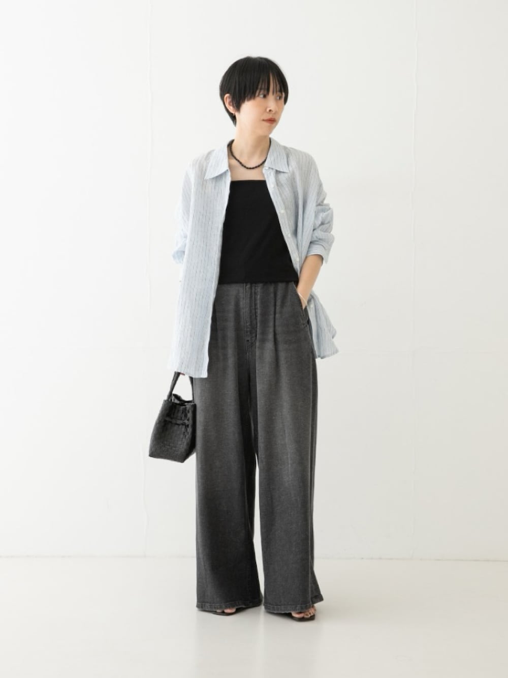 ブラック系のデニムパンツ、ブラック系のトートバッグ、ブルー系のシャツ/ブラウスを着用したレディースの夏コーディネートの3枚目の写真