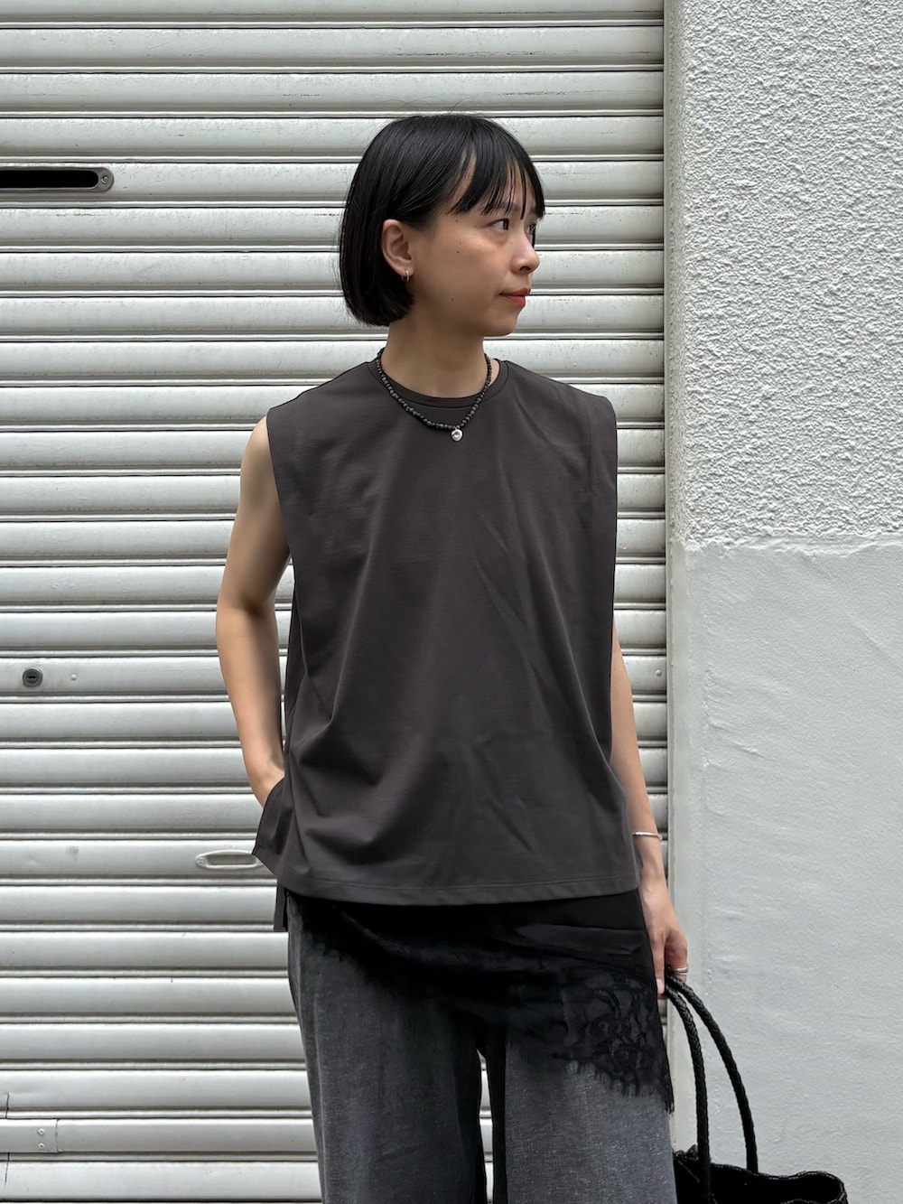 ブラック系のキャミソール、ブラック系のデニムパンツ、ブラック系のトートバッグを着用したレディースの夏コーディネートの3枚目の写真