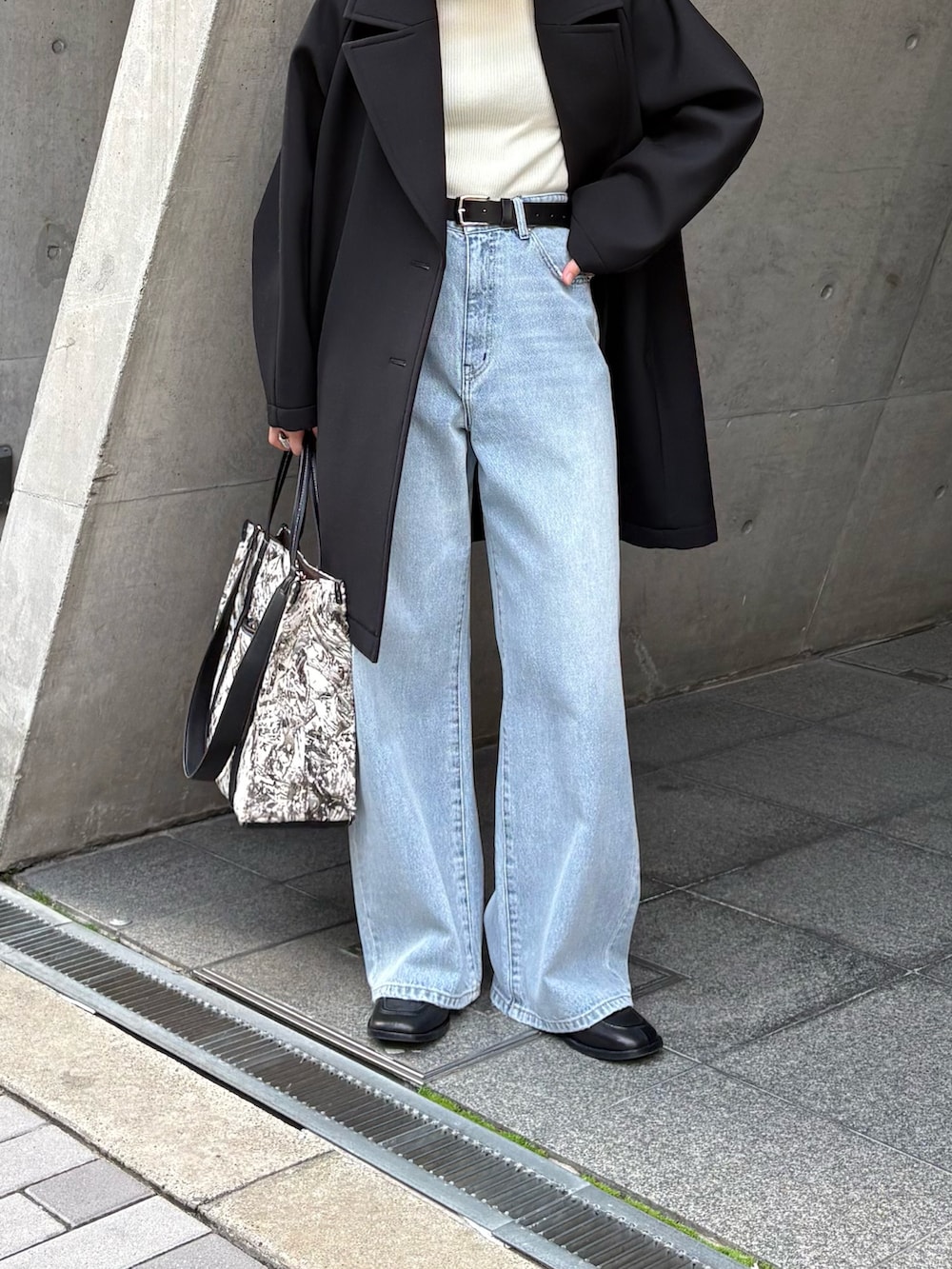 ブラック系のチェスターコート、ホワイト系のニット/セーター、ブラック系のローファーを着用したレディースの冬コーディネートの3枚目の写真