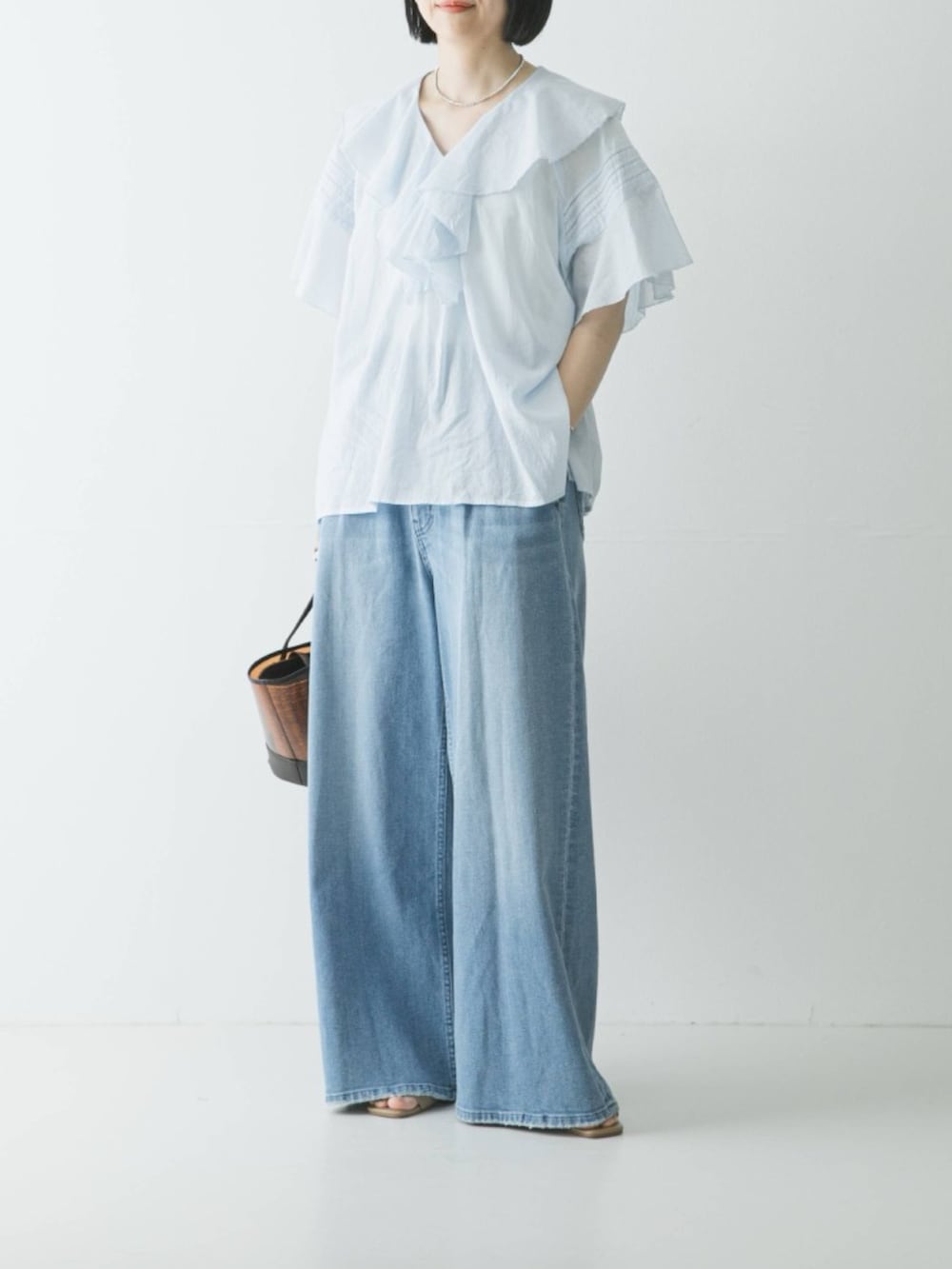 ブルー系のシャツ/ブラウス、ブルー系のデニムパンツ、ブラウン系のかごバッグを着用したレディースの春コーディネートの2枚目の写真