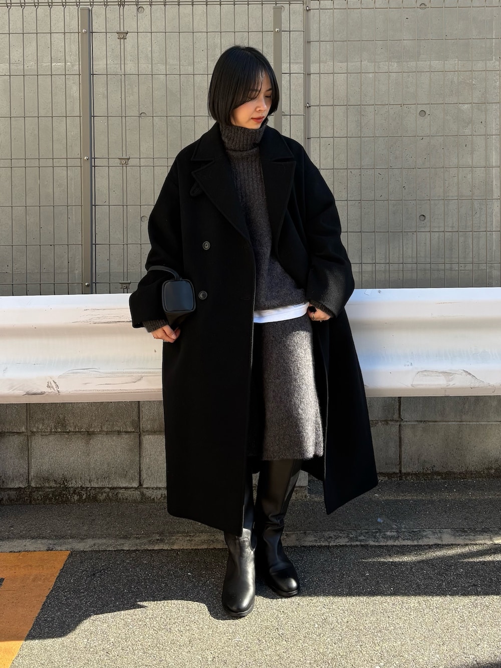 ブラック系のチェスターコート、グレー系のニット/セーター、グレー系のその他パンツを着用したレディースの冬コーディネートの2枚目の写真