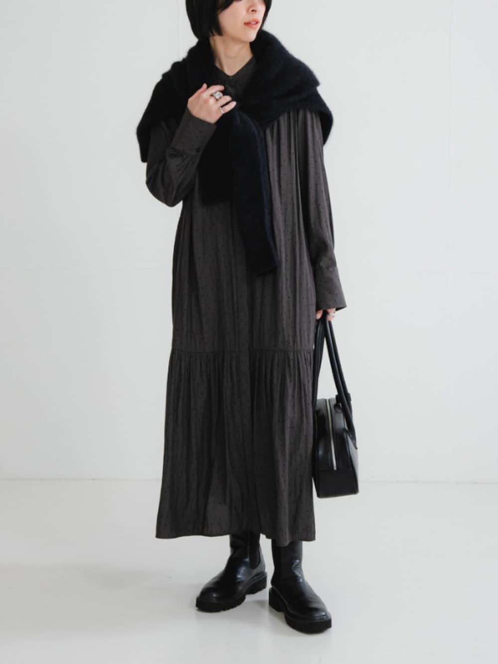 ブラック系のニット/セーター、グリーン系のワンピース、ブラック系のブーツを着用したレディースの冬コーディネートの2枚目の写真