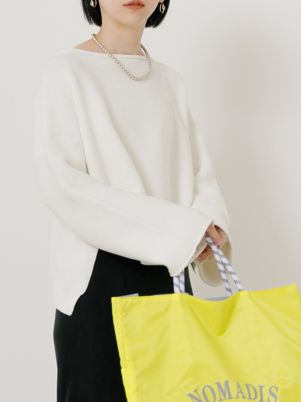 ホワイト系のニット/セーター、ブラック系のスカート、シルバー系のスニーカーを着用したレディースの冬コーディネートの2枚目の写真