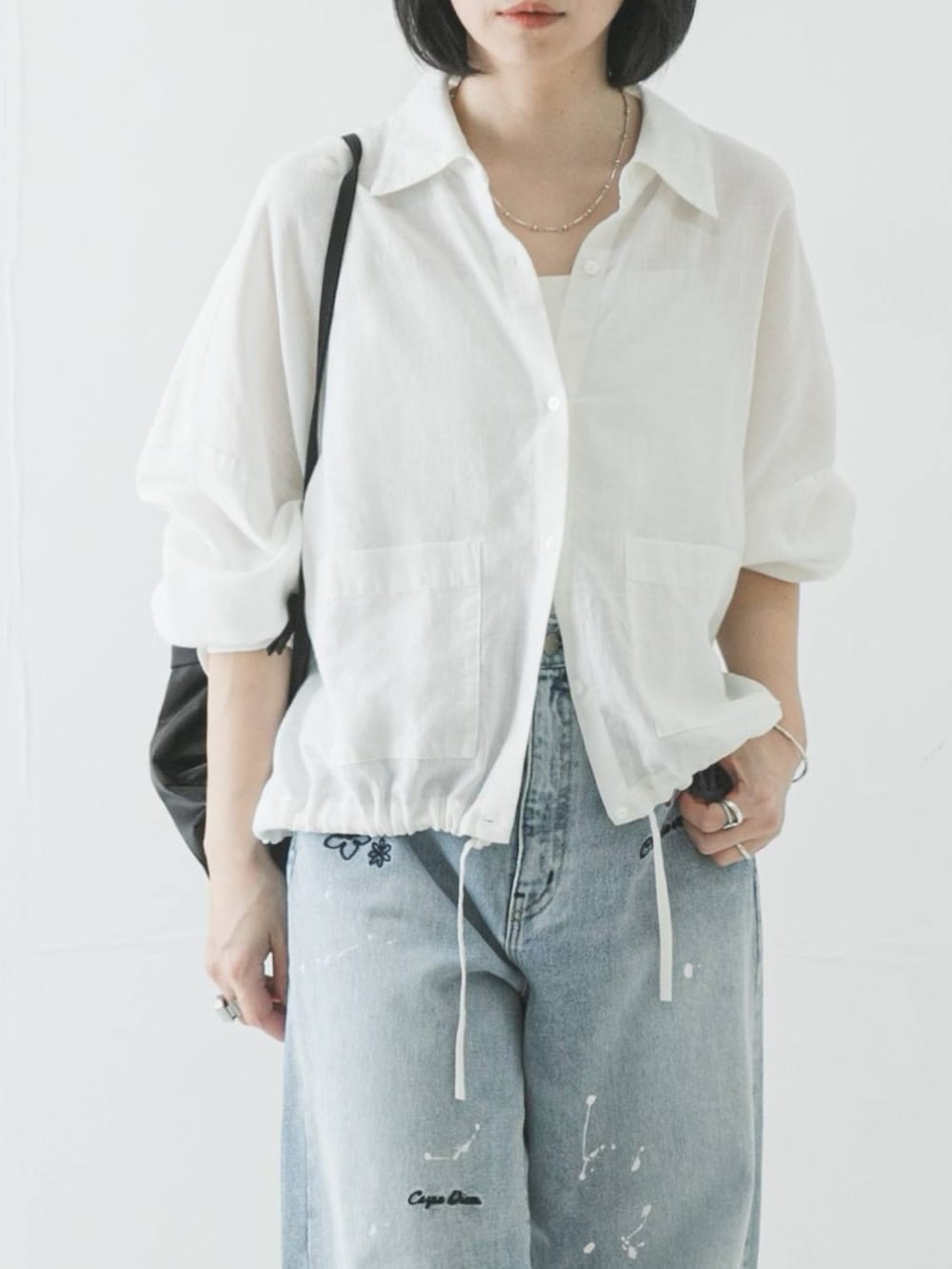 ホワイト系のシャツ/ブラウス、ブラック系のバックパック/リュック、ブルー系のデニムパンツを着用したレディースの春コーディネートの3枚目の写真