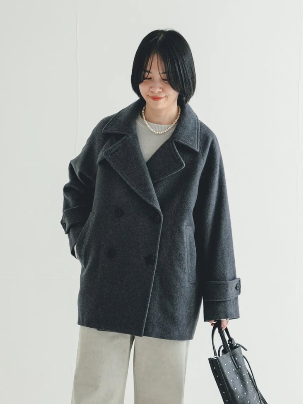 ブラック系のトートバッグ、グレー系のデニムパンツ、グレー系のピーコートを着用したレディースの冬コーディネートの3枚目の写真