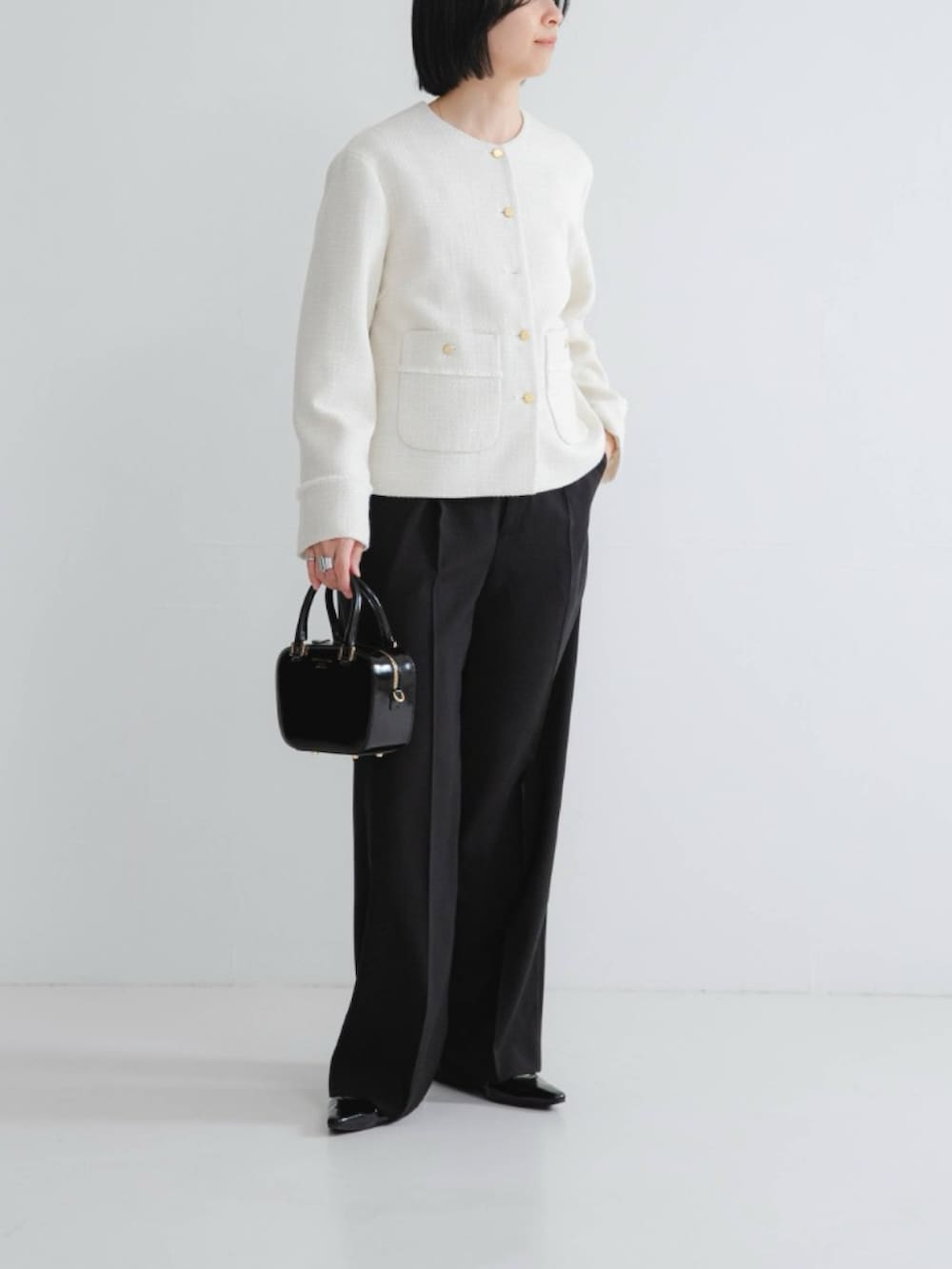 ホワイト系のノーカラージャケット、ブラック系のその他パンツ、ブラック系のパンプスを着用したレディースの冬コーディネートの2枚目の写真