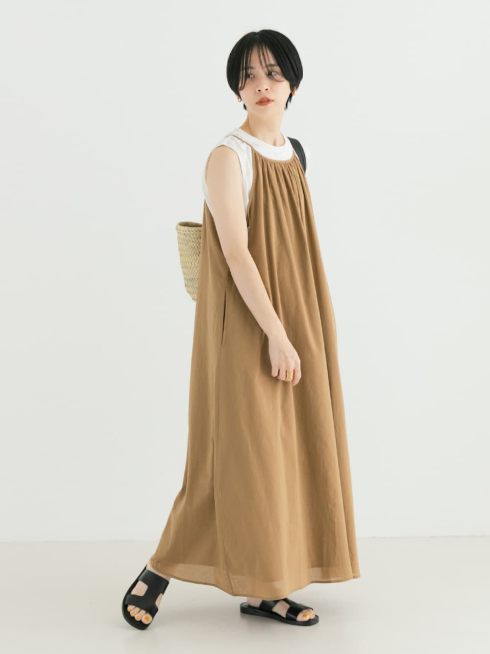 ベージュ系のワンピース、ブラック系のかごバッグを着用したレディースの春コーディネートの2枚目の写真