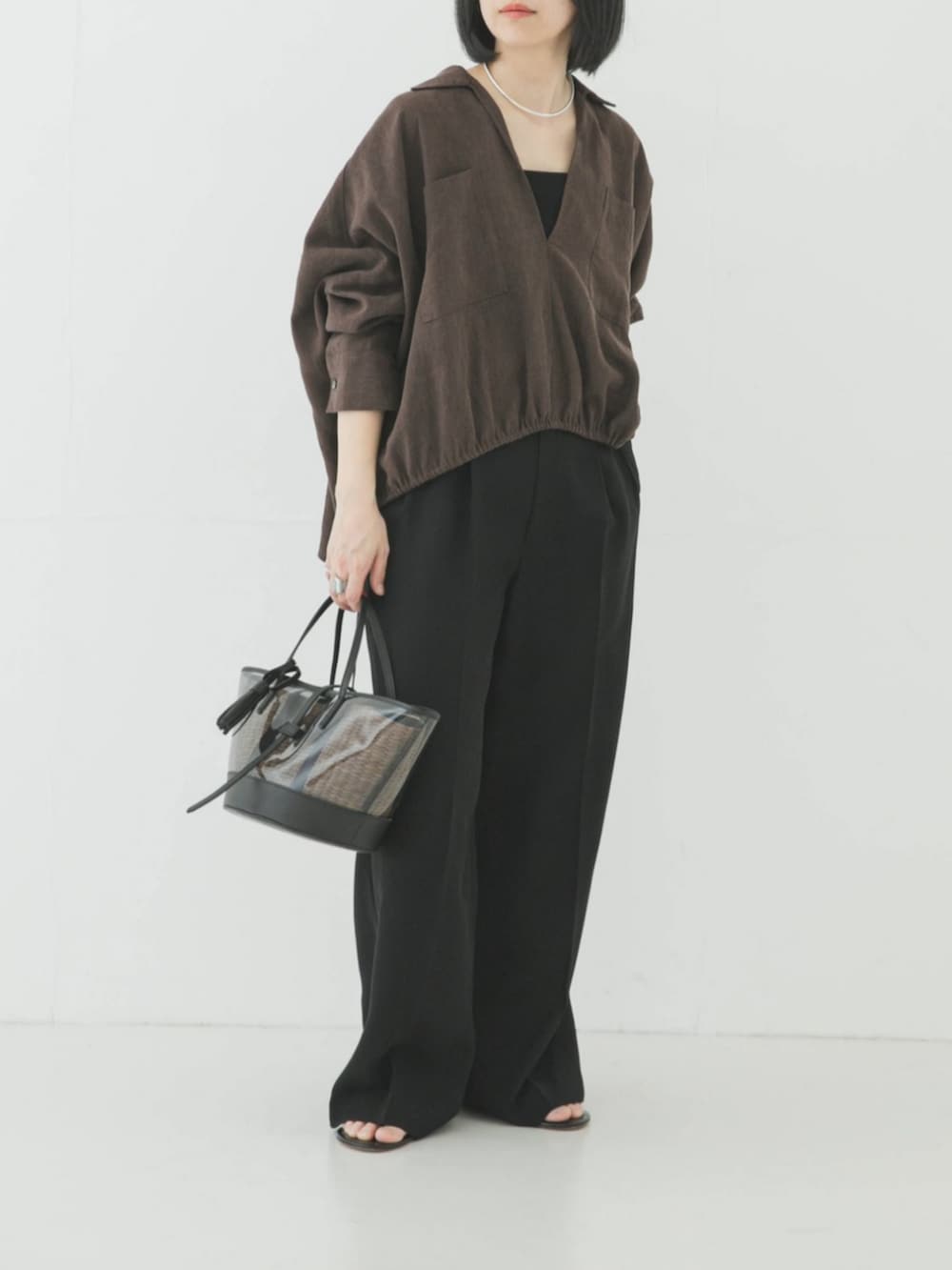 ブラック系のその他パンツ、ブラウン系のシャツ/ブラウス、シルバー系のネックレスを着用したレディースの春コーディネートの2枚目の写真