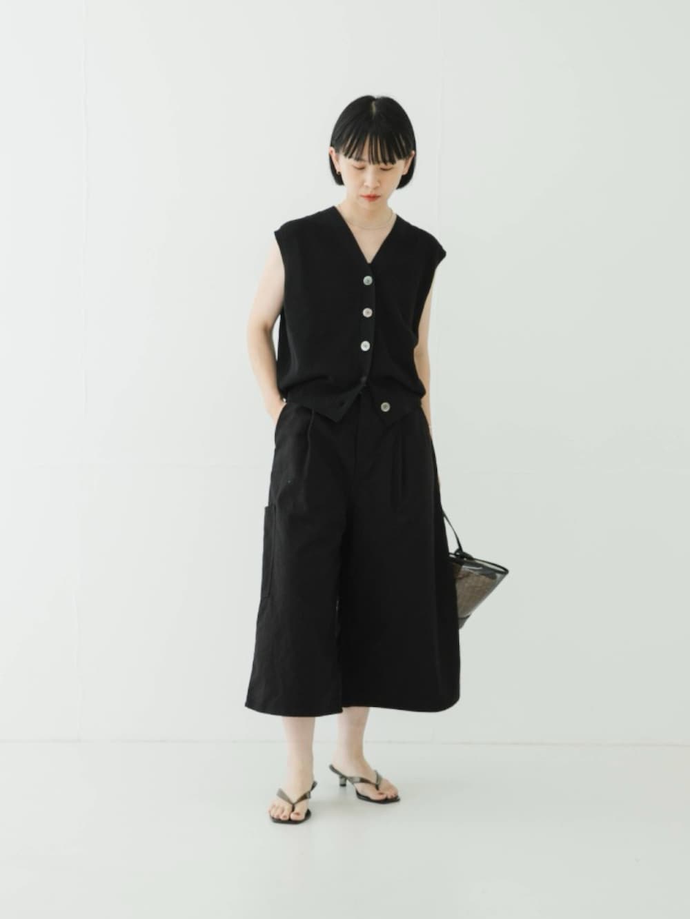 ブラック系のベスト、ブラック系のかごバッグ、ブラック系のその他パンツを着用したレディースの夏コーディネートの2枚目の写真