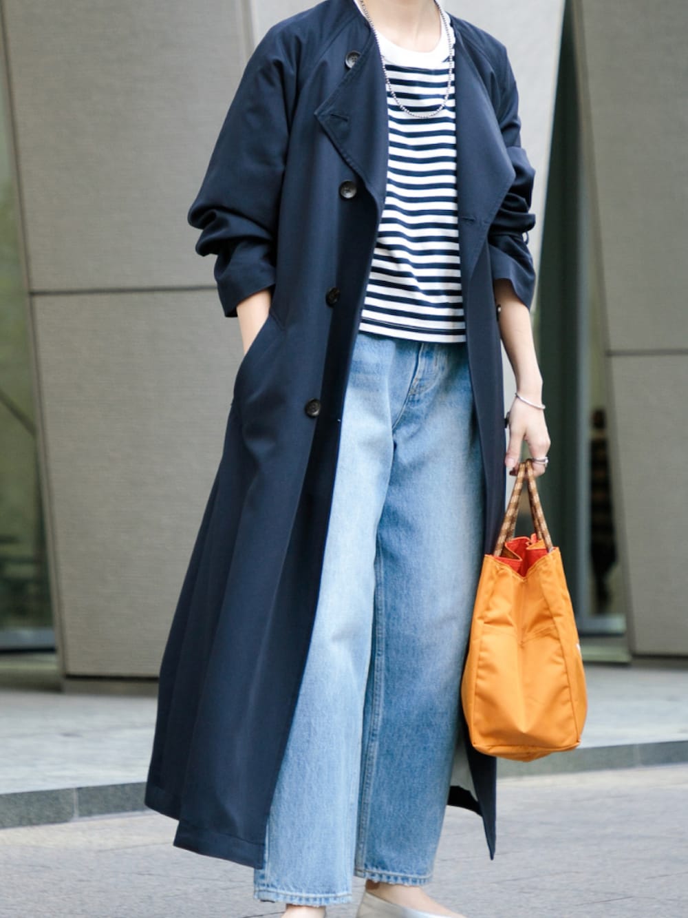 ブルー系のトレンチコート、ブラウン系のトートバッグ、ホワイト系のデニムパンツを着用したレディースの春コーディネートの2枚目の写真