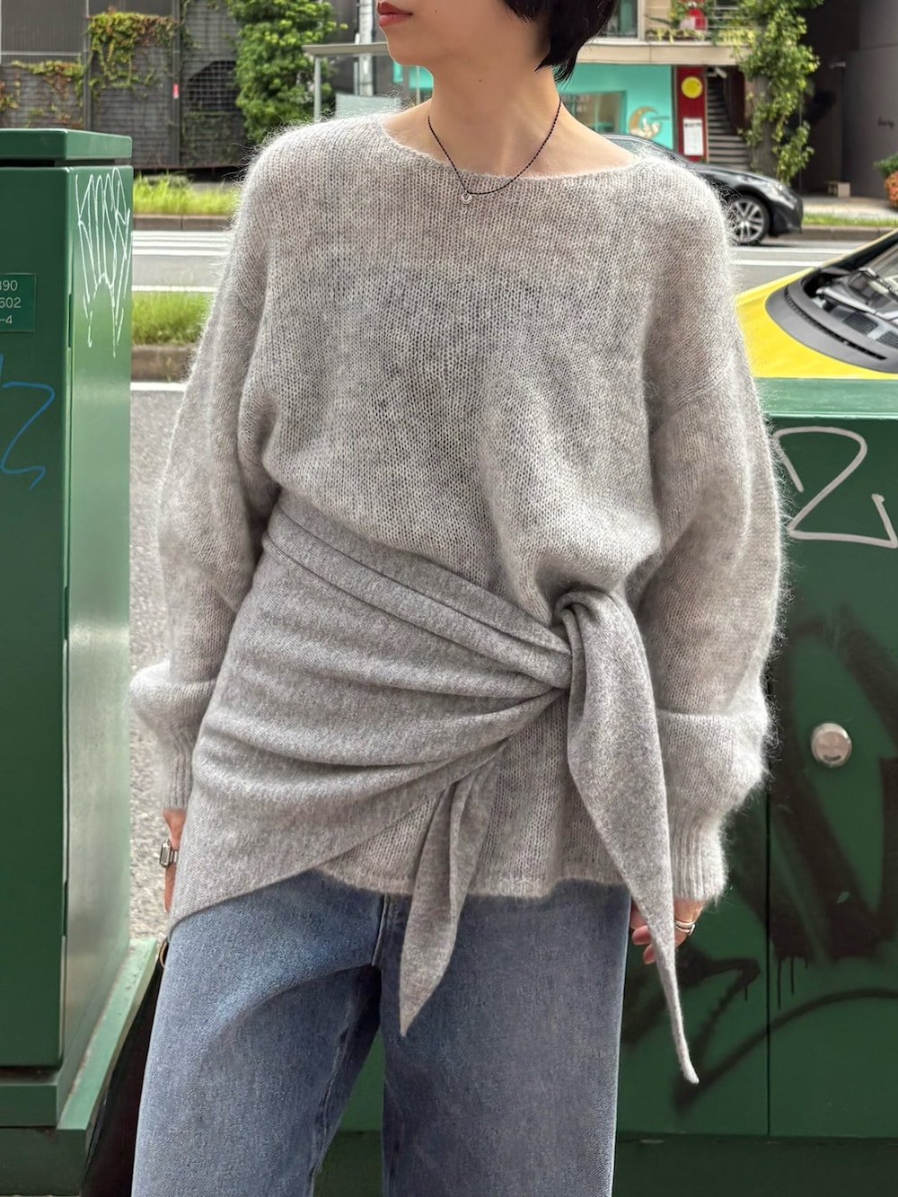 グレー系のニット/セーター、ブルー系のデニムパンツ、ブラック系のショルダーバッグを着用したレディースの秋コーディネートの3枚目の写真