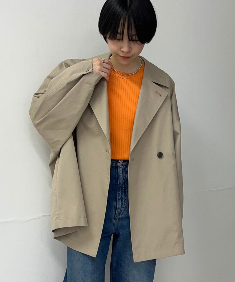 ベージュ系のトレンチコート、オレンジ系のニット/セーターを着用したレディースの春コーディネートの2枚目の写真