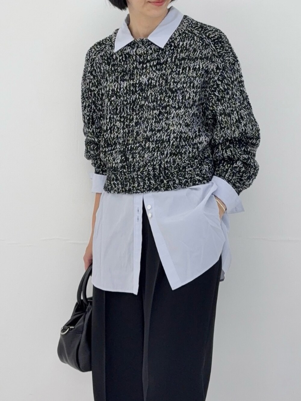 ブラック系のニット/セーター、ブルー系のシャツ/ブラウス、ブラック系のハンドバッグを着用したレディースの冬コーディネートの3枚目の写真