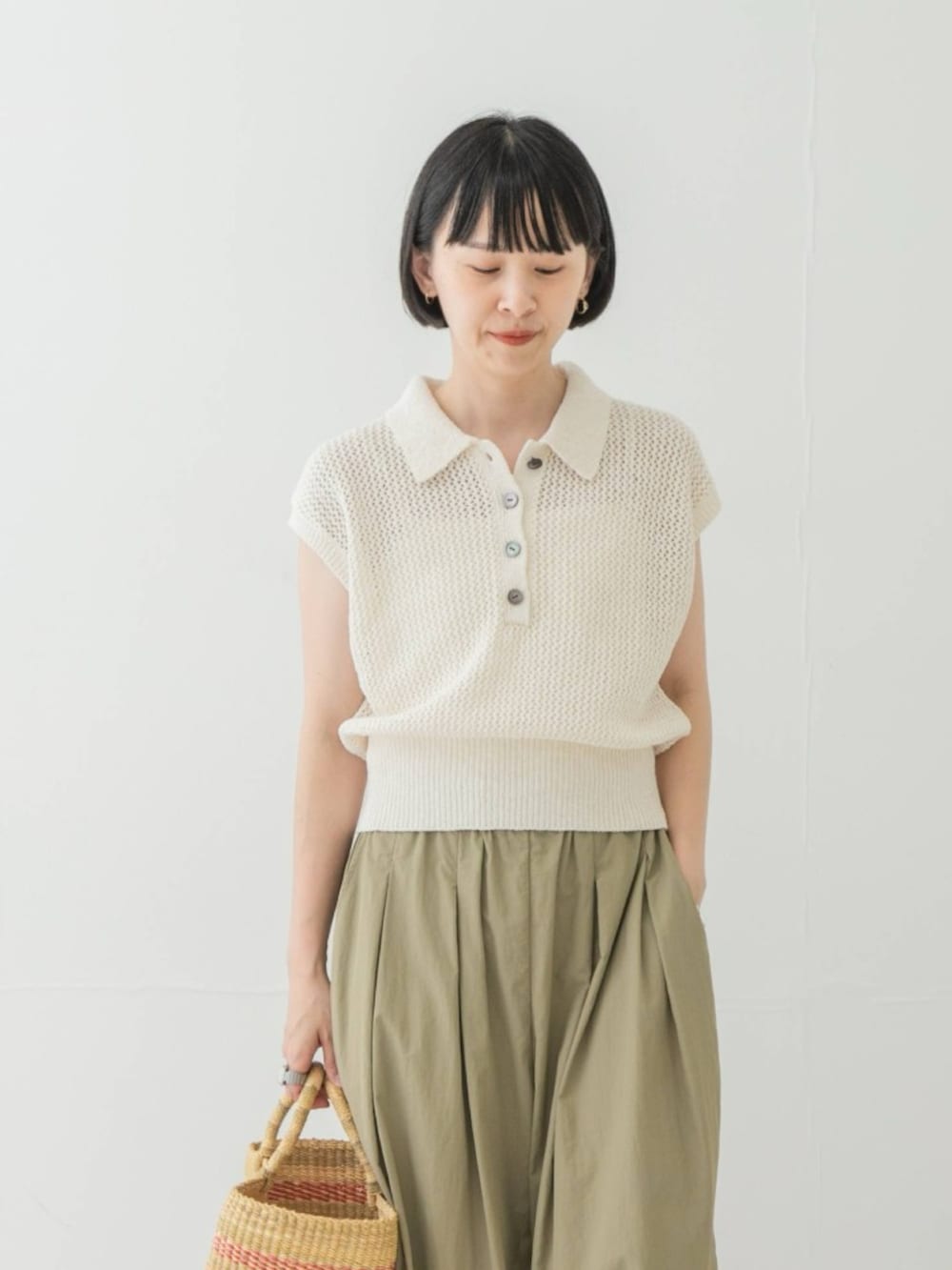 ホワイト系のニット/セーター、ベージュ系のかごバッグ、ベージュ系のその他パンツを着用したレディースの夏コーディネートの2枚目の写真