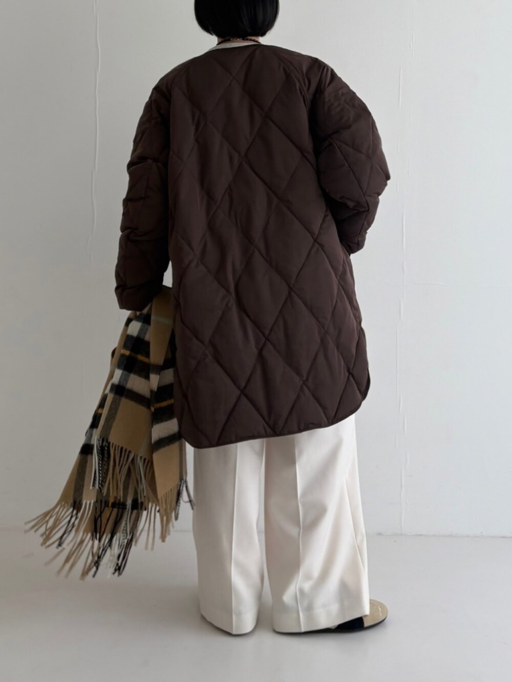 ベージュ系のスニーカー、ホワイト系のその他パンツ、ブラウン系のダウンジャケット/コートを着用したレディースの秋コーディネートの3枚目の写真