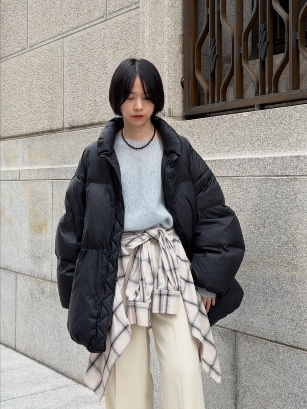 ベージュ系のブーツ、ブルー系のニット/セーター、ブラック系のダウンジャケット/コートを着用したレディースの秋コーディネートの5枚目の写真