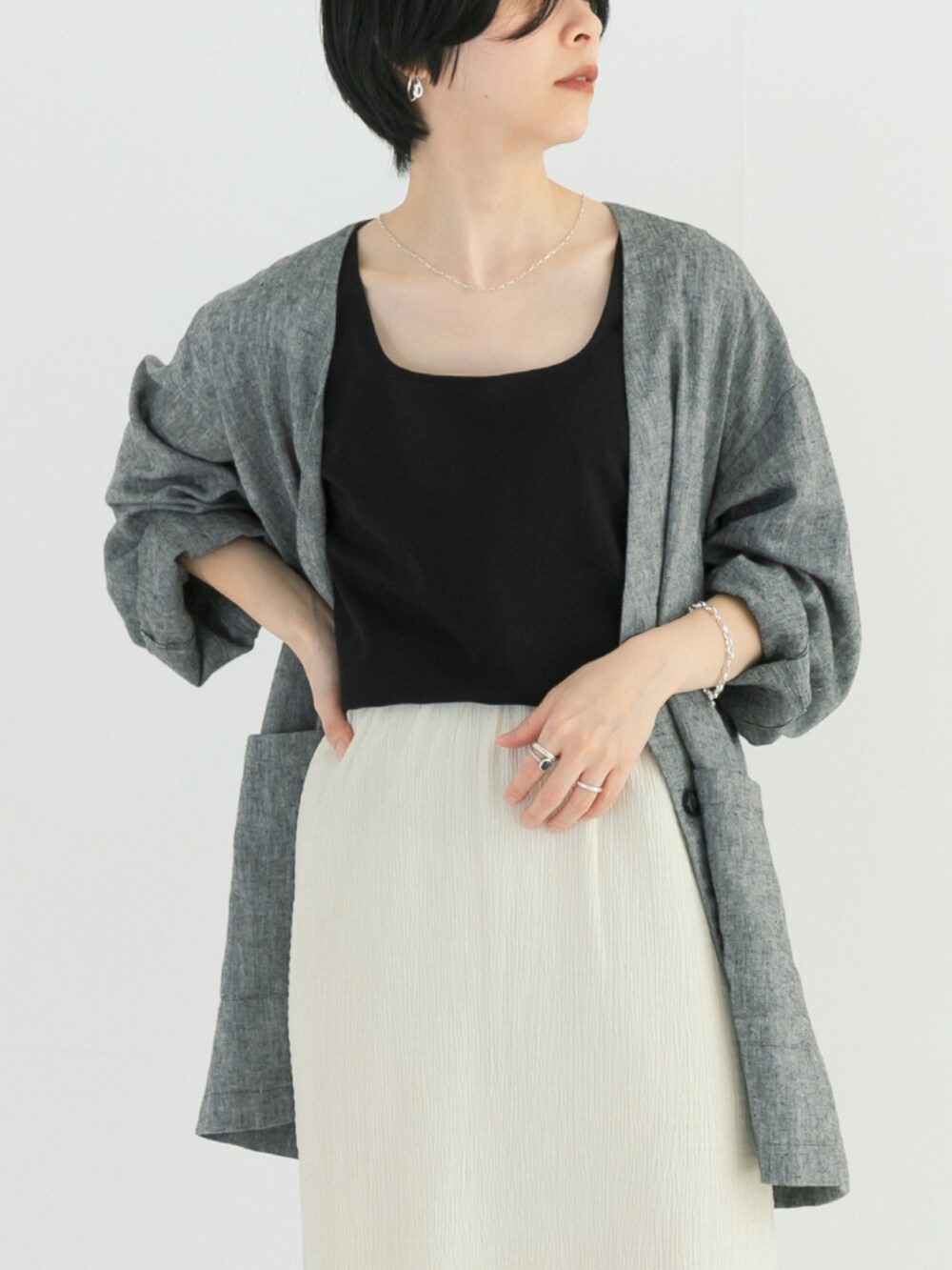 ブラック系のタンクトップ、ブラック系のノーカラージャケット、ホワイト系のスカートを着用したレディースの春コーディネートの2枚目の写真