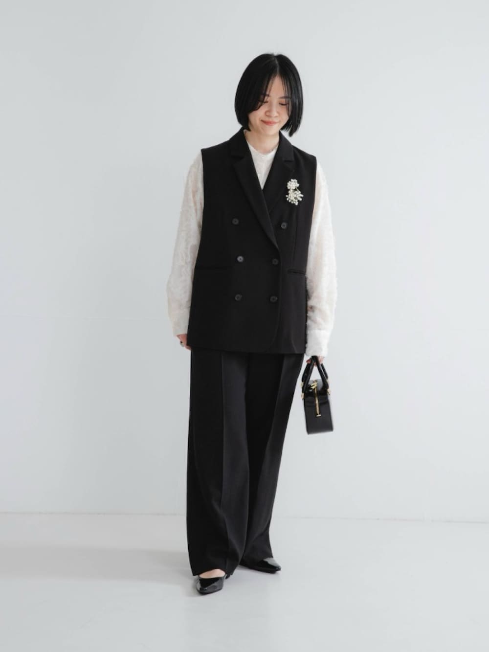 ホワイト系のシャツ/ブラウス、ブラック系のその他アウター、ブラック系のその他パンツを着用したレディースの冬コーディネートの2枚目の写真