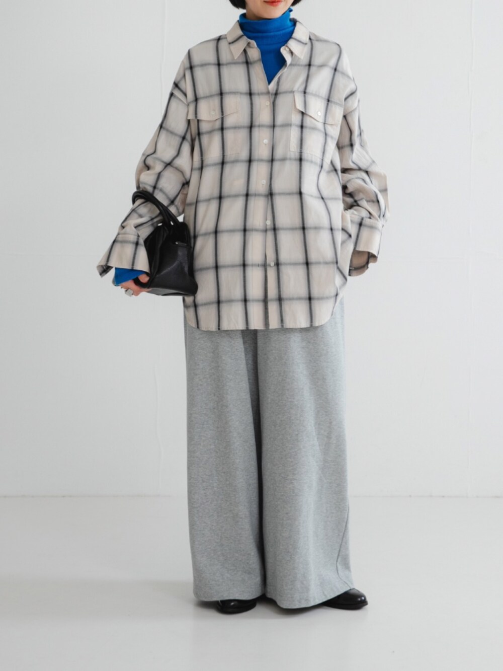 ブルー系のTシャツ/カットソー、ホワイト系のシャツ/ブラウス、ブラック系のハンドバッグを着用したレディースの秋コーディネートの2枚目の写真