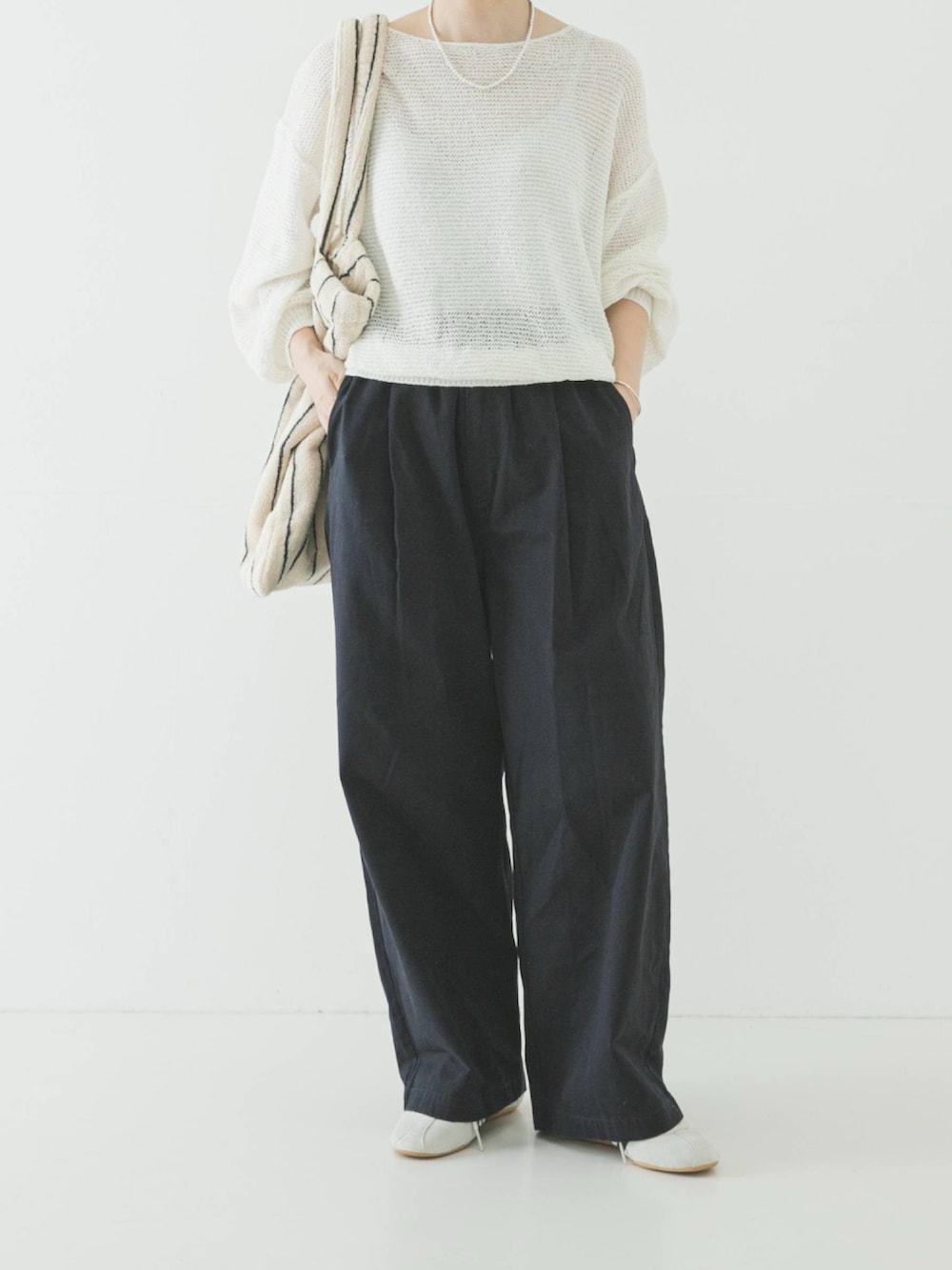 ホワイト系のニット/セーター、ホワイト系のトートバッグ、ブルー系のその他パンツを着用したレディースの春コーディネートの2枚目の写真