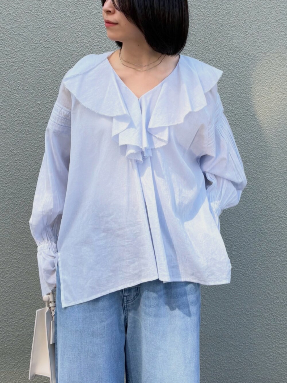 ブルー系のシャツ/ブラウス、ブルー系のデニムパンツ、ホワイト系のハンドバッグを着用したレディースの春コーディネートの3枚目の写真