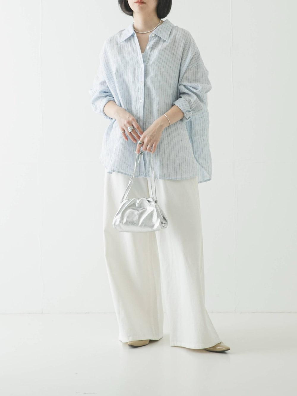 ブルー系のシャツ/ブラウス、シルバー系のショルダーバッグ、ホワイト系のデニムパンツを着用したレディースの春コーディネートの2枚目の写真