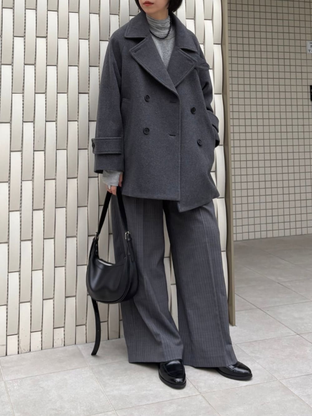 グレー系のピーコート、グリーン系のニット/セーター、グレー系のその他パンツを着用したレディースの秋コーディネートの2枚目の写真