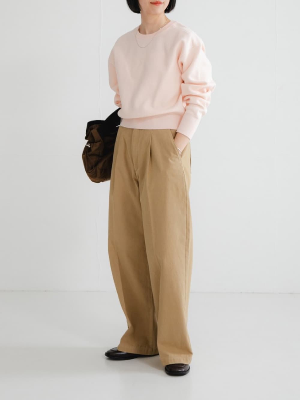 ピンク系のニット/セーター、ブラウン系のショルダーバッグ、ブラウン系のローファーを着用したレディースの冬コーディネートの2枚目の写真