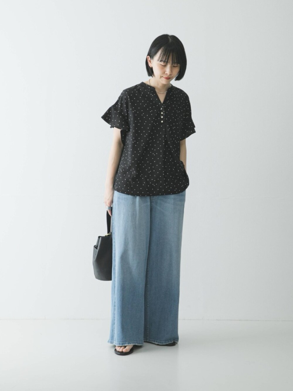 ブラック系のシャツ/ブラウス、ブルー系のデニムパンツ、ブラック系のハンドバッグを着用したレディースの春コーディネートの2枚目の写真