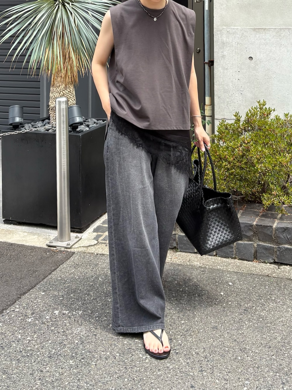ブラック系のキャミソール、ブラック系のデニムパンツ、ブラック系のトートバッグを着用したレディースの夏コーディネートの2枚目の写真