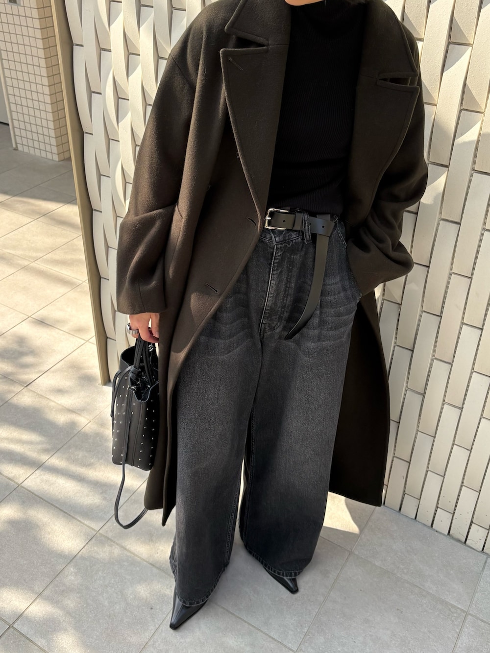 グリーン系のチェスターコート、ブラック系のニット/セーター、ブラック系のデニムパンツを着用したレディースの冬コーディネートの6枚目の写真