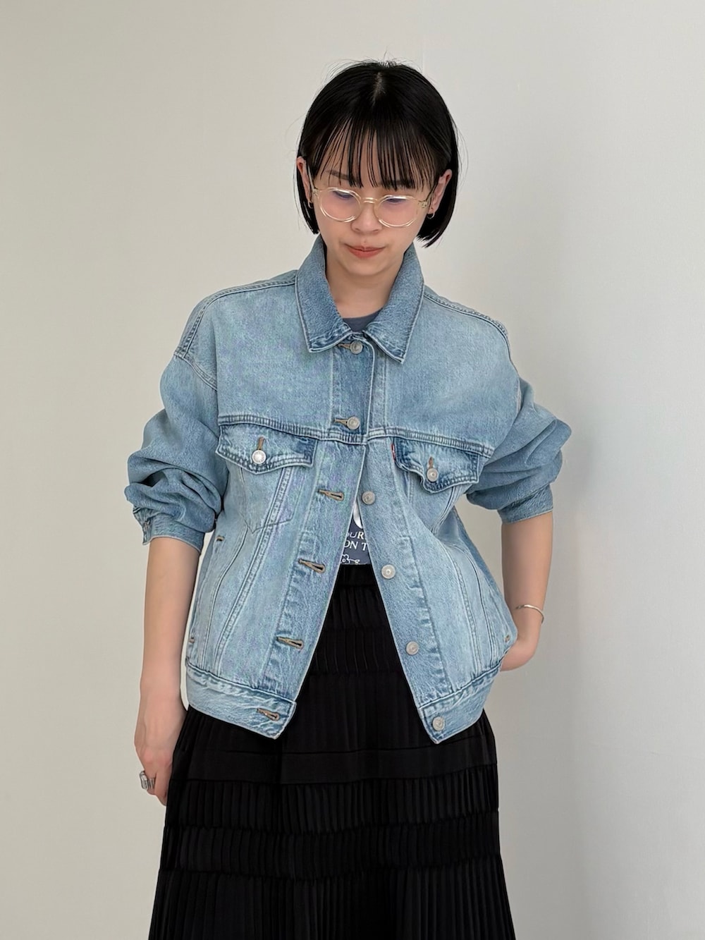 ブルー系のデニムジャケット、ブラウン系のバックパック/リュック、ブラック系のスカートを着用したレディースの春コーディネートの2枚目の写真