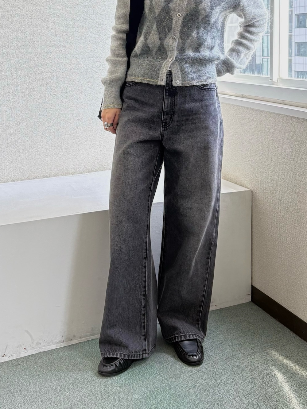 グレー系のニット/セーター、ブラック系のトートバッグ、ブラック系のデニムパンツを着用したレディースの秋コーディネートの3枚目の写真