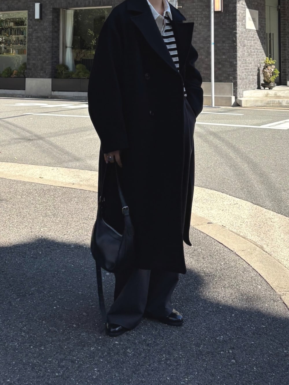 ブラック系のチェスターコート、グレー系のTシャツ/カットソー、グレー系のTシャツ/カットソーを着用したレディースの秋コーディネートの4枚目の写真