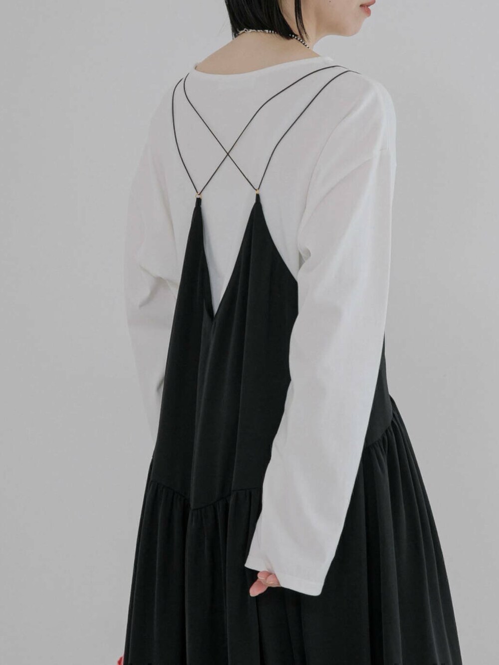 ホワイト系のTシャツ/カットソー、ブラック系のワンピース、ブラック系のブーツを着用したレディースの冬コーディネートの2枚目の写真