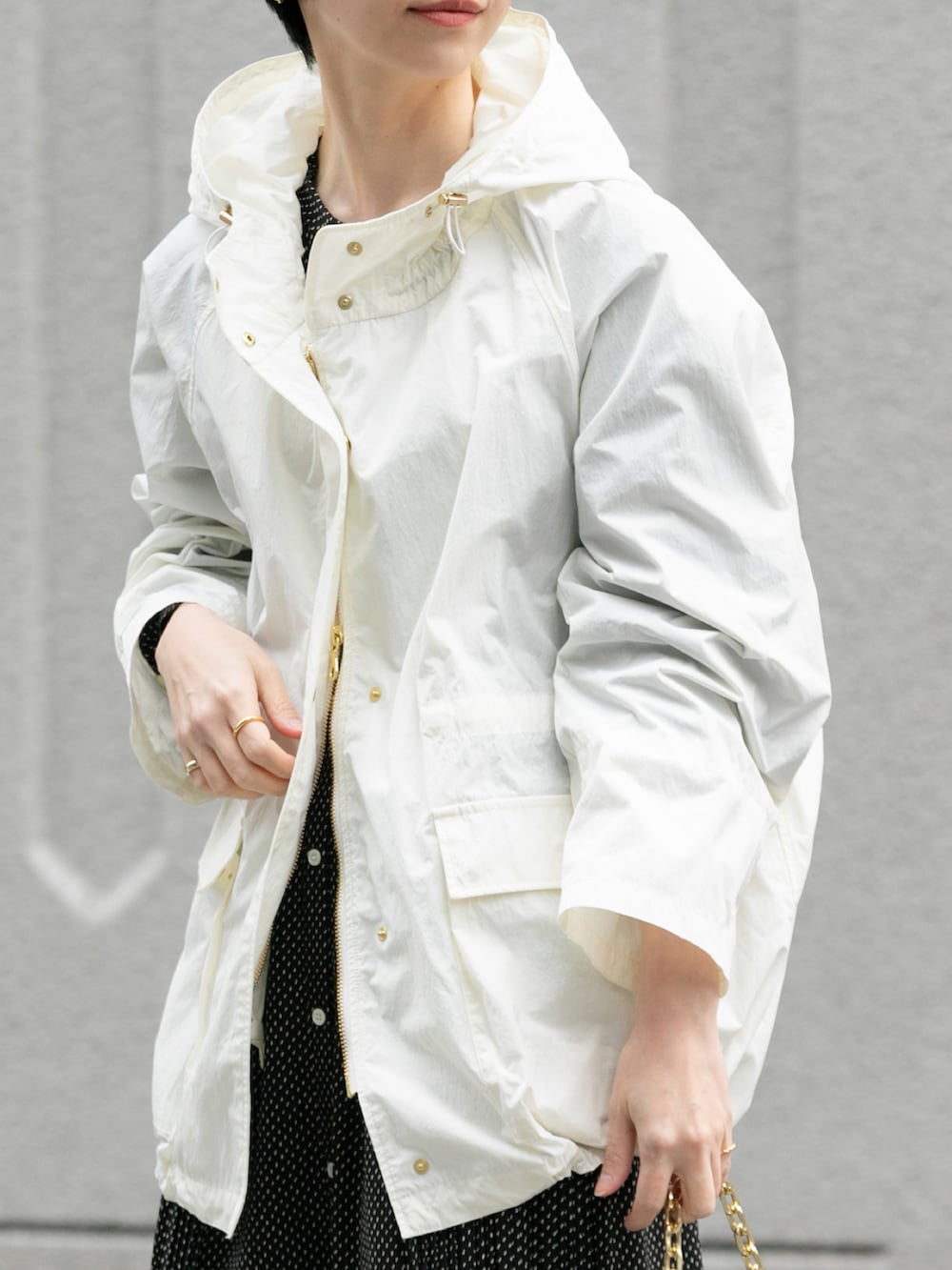 ホワイト系のマウンテンパーカー、ブラック系のショルダーバッグ、ブラック系のワンピースを着用したレディースの春コーディネートの3枚目の写真