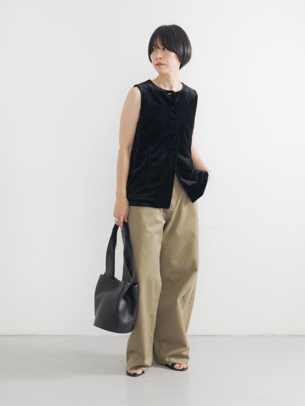 ブラック系のベスト、ベージュ系のその他パンツ、ブラック系のハンドバッグを着用したレディースの夏コーディネートの3枚目の写真