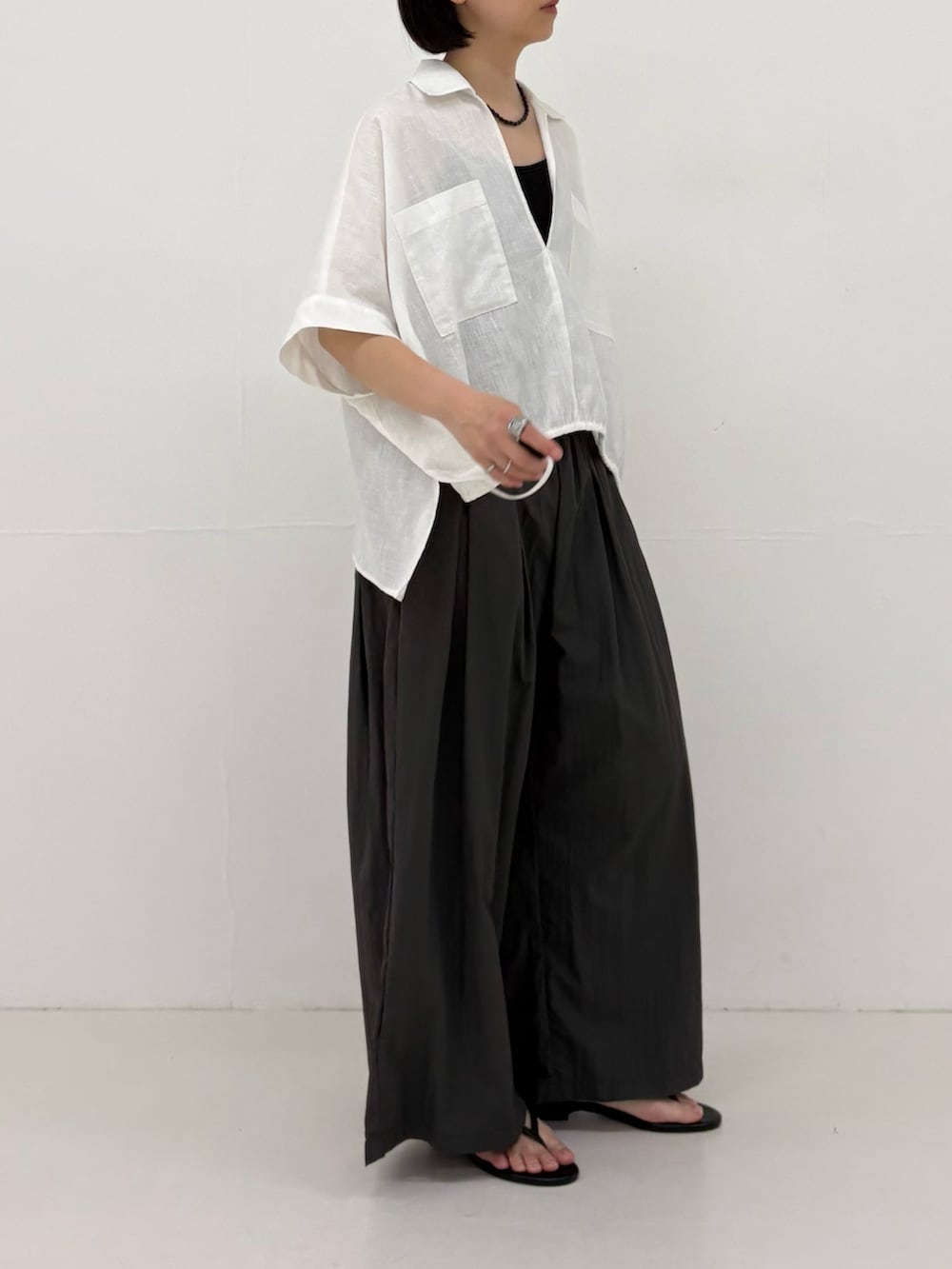 グレー系のその他パンツ、ホワイト系のシャツ/ブラウス、ブラック系のサンダルを着用したレディースの春コーディネートの3枚目の写真