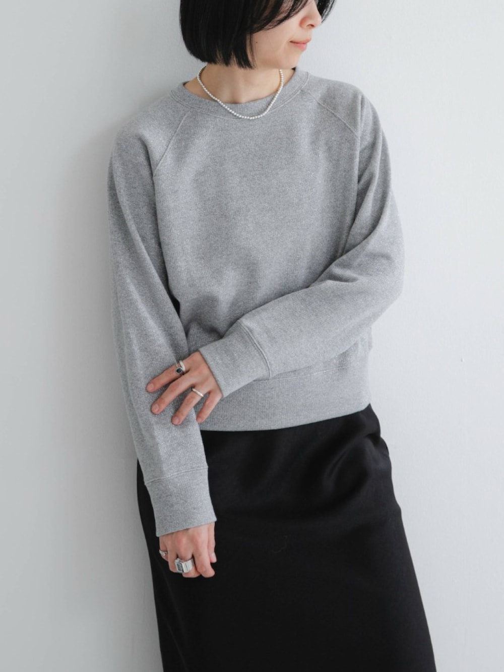 グレー系のスウェット、ブラック系のスカート、ブラック系のスニーカーを着用したレディースの冬コーディネートの3枚目の写真