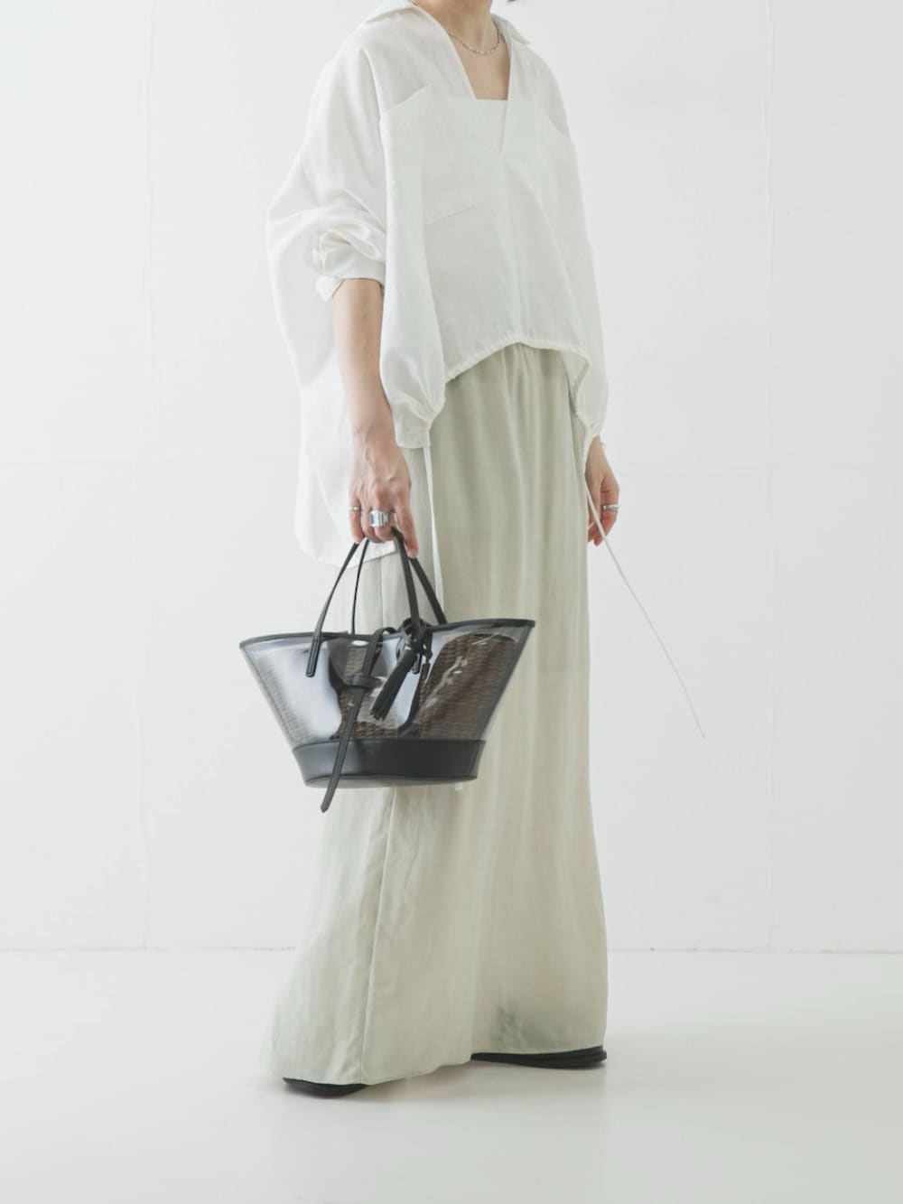 ホワイト系のシャツ/ブラウス、ブラック系のかごバッグ、ベージュ系のスカートを着用したレディースの春コーディネートの2枚目の写真