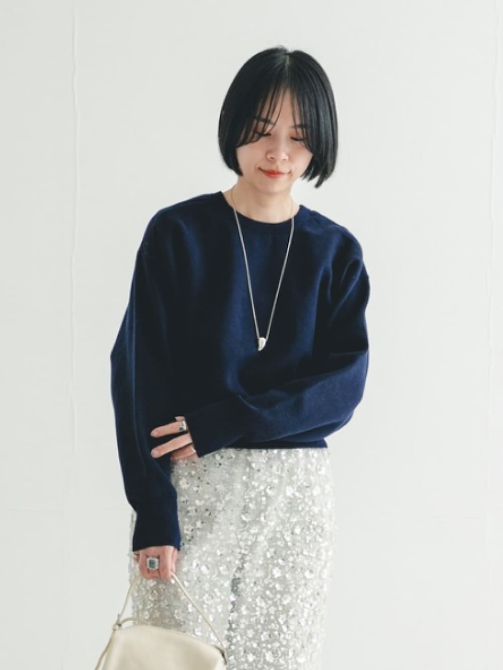 グレー系のデニムパンツ、ホワイト系のスカート、ブラック系のブーツを着用したレディースの冬コーディネートの2枚目の写真