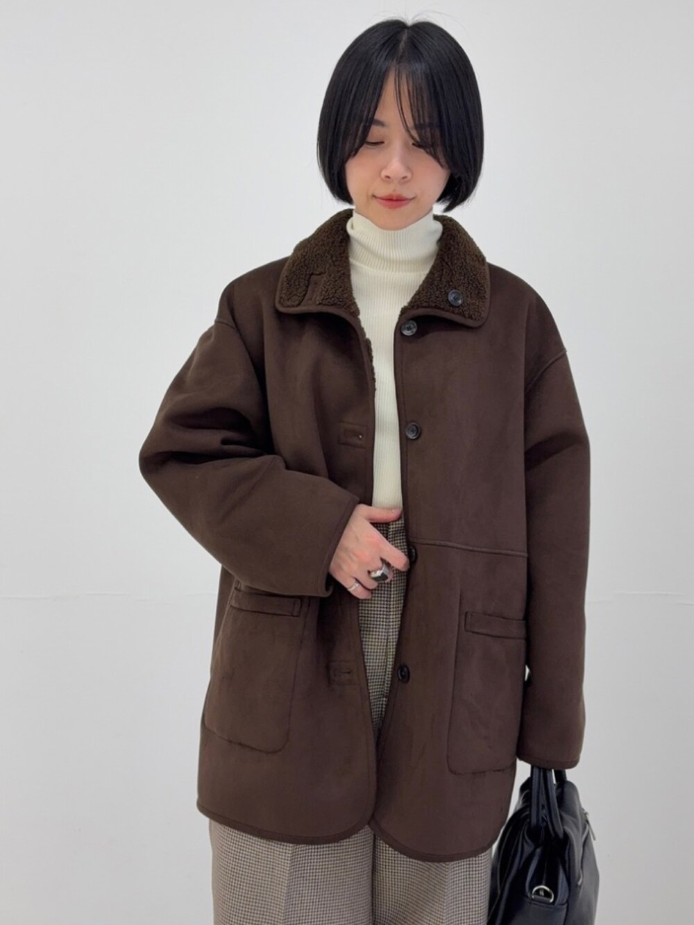 ホワイト系のニット/セーター、ブラウン系のムートンコート、ベージュ系のスニーカーを着用したレディースの秋コーディネートの2枚目の写真