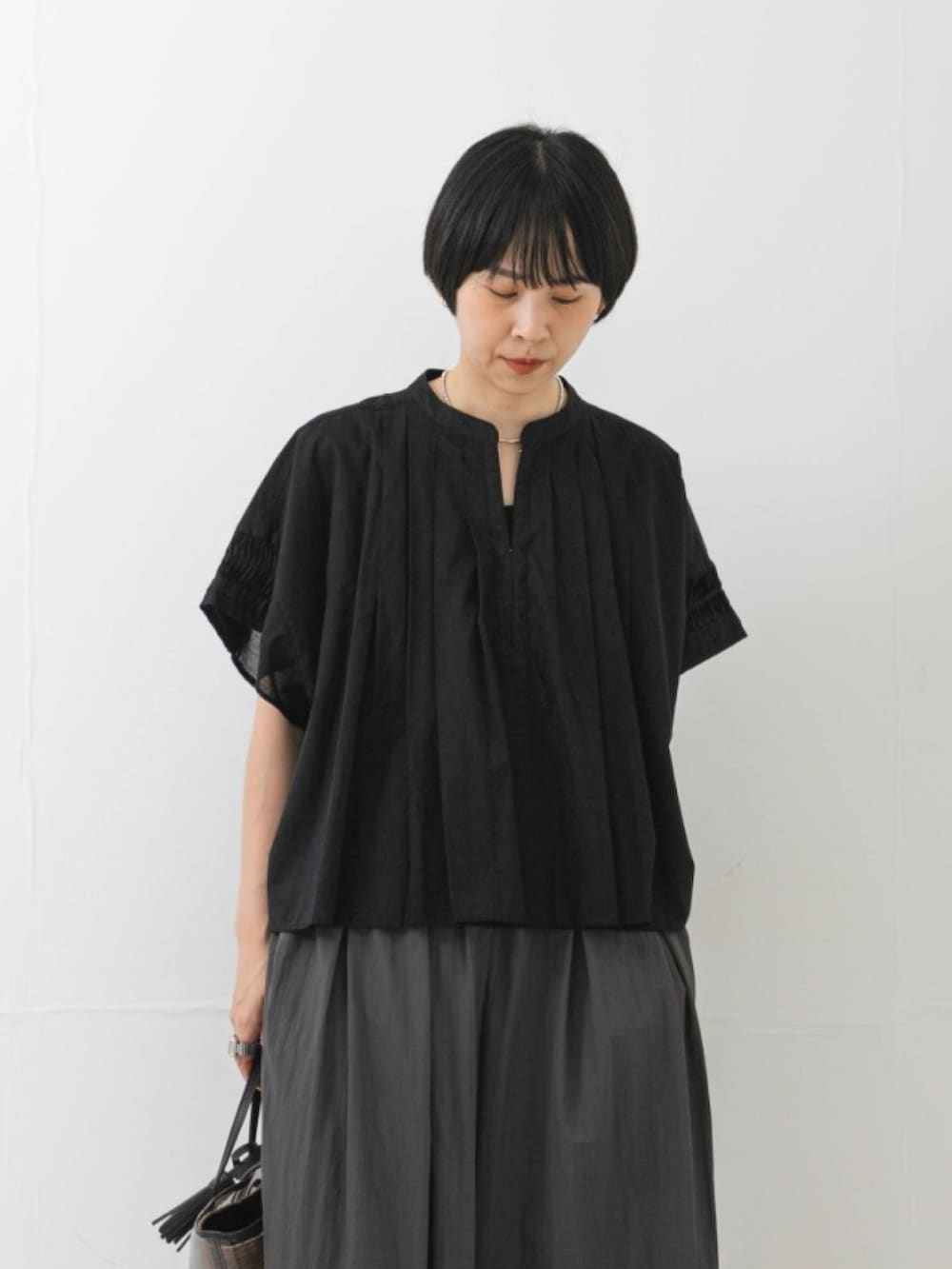ブラック系のシャツ/ブラウス、ブラック系のかごバッグ、グレー系のその他パンツを着用したレディースの夏コーディネートの2枚目の写真