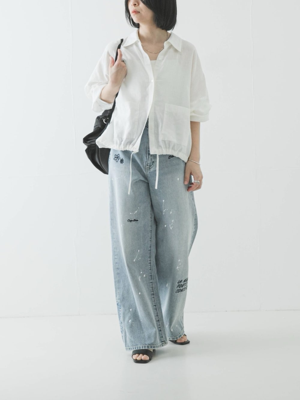 ホワイト系のシャツ/ブラウス、ブラック系のバックパック/リュック、ブルー系のデニムパンツを着用したレディースの春コーディネートの2枚目の写真