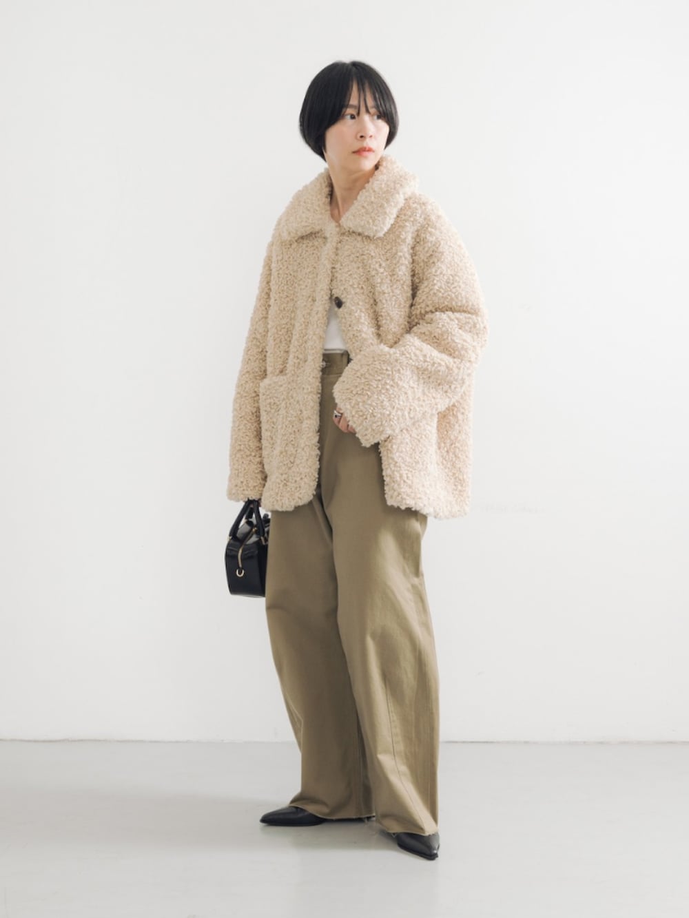 ホワイト系のその他アウター、ブラック系のブーツ、ブラック系のショルダーバッグを着用したレディースの秋コーディネートの2枚目の写真