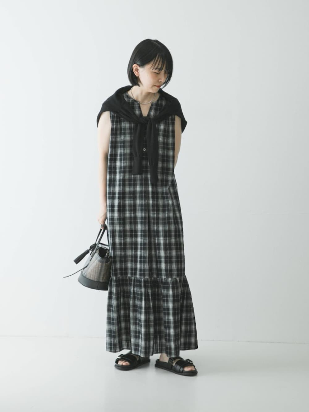 ブラック系のカーディガン/ボレロ、ブラック系のワンピース、ブラック系のサンダルを着用したレディースの春コーディネートの2枚目の写真