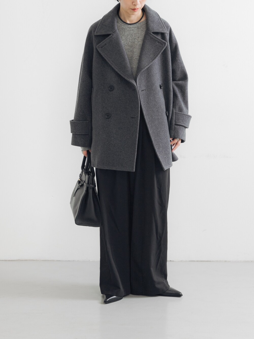 グレー系のピーコート、ブラック系のブーツ、ブラック系のトートバッグを着用したレディースの夏コーディネートの3枚目の写真